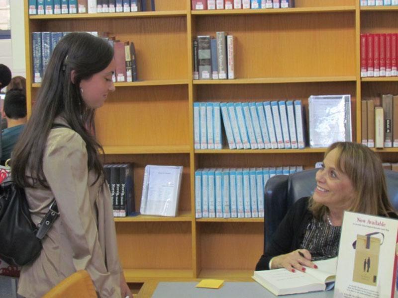 Laura+Schoff+speaks+to+a+student+while+signing+her+book+in+the+Media+Center.